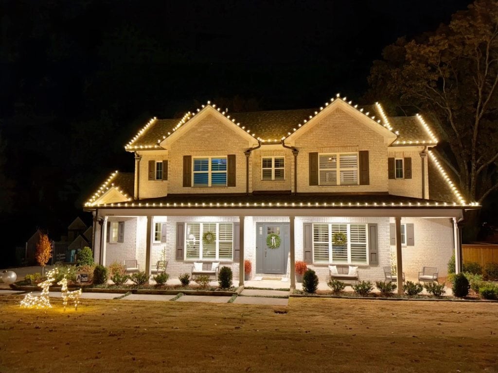 Beautiful house decorated with warm white Christmas lights at night.